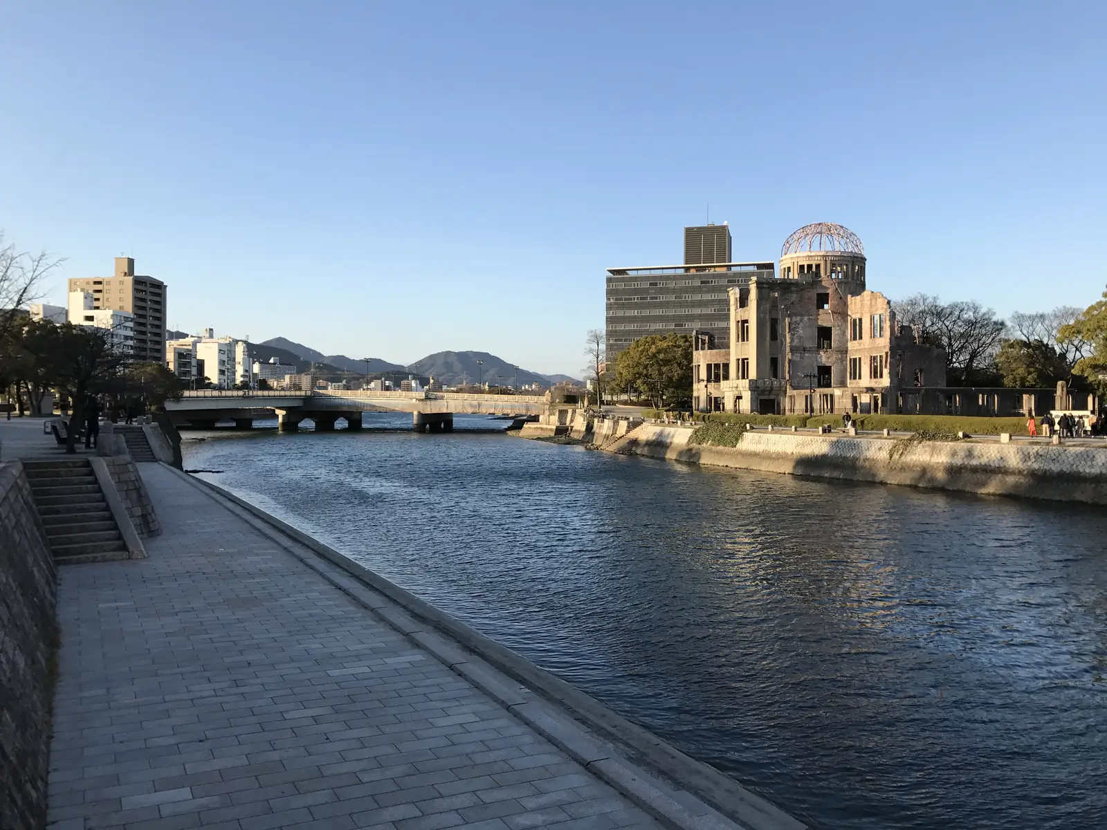 The Atomic Bomb Dome and the T-shaped Aioi Bridge seen from the riverside walk in Peace Memorial Park in late afternoon light