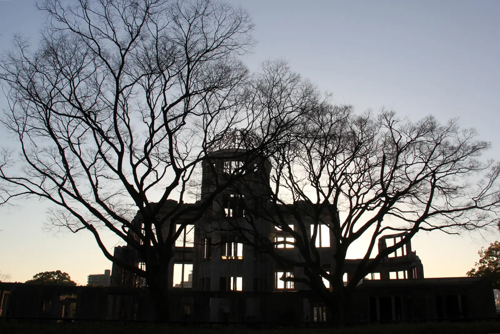 The Atomic Bomb Dome in silhouette at dusk behind bare winter trees