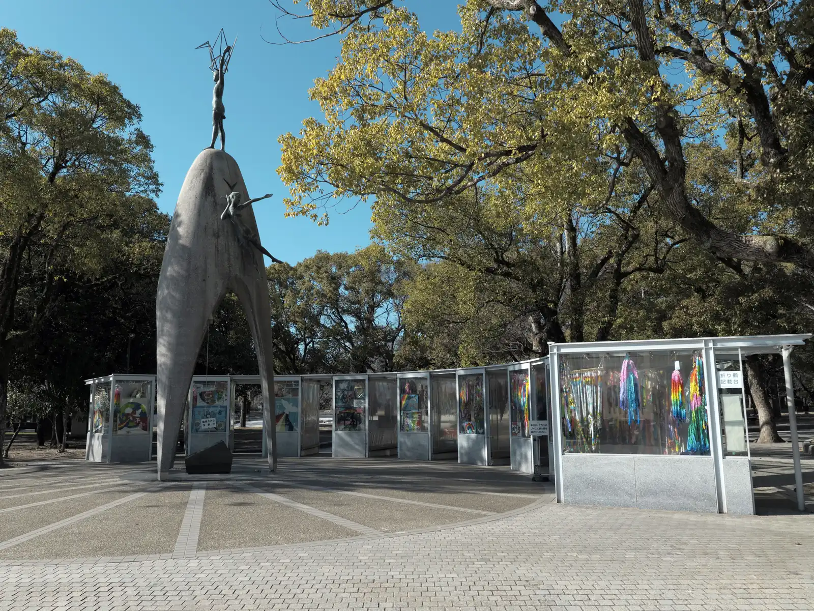 The tall Children’s Peace Monument with a figure of a girl holding a crane on top, and glass booths full of paper cranes around it