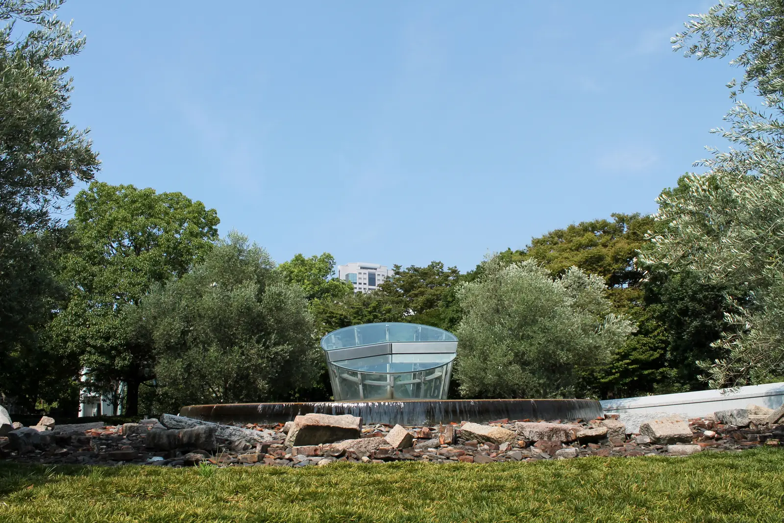 The glass cone and ring of stones of the Hiroshima National Peace Memorial Hall's surface memorial among trees