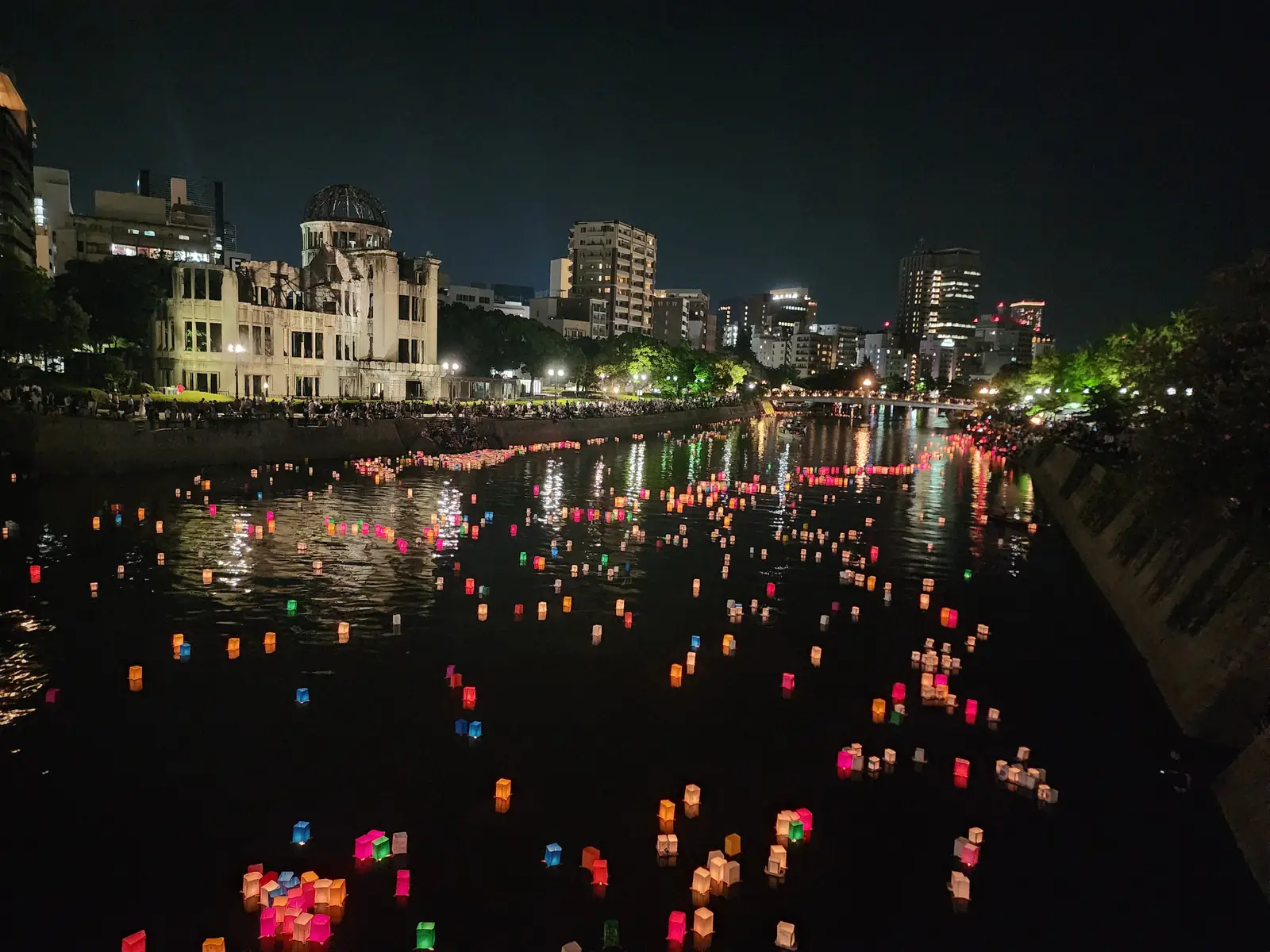 Paper lanterns floating on the Motoyasu River on the evening of 6 August, with the lit Atomic Bomb Dome behind